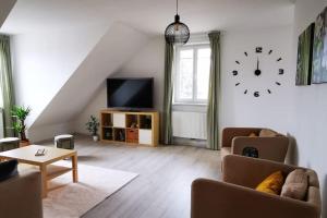 a living room with a couch and a clock on the wall at Vienna's Nature Corner - charming rooftop family apartment in Gerasdorf bei Wien