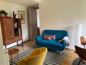 ein Wohnzimmer mit einem blauen Sofa und 2 Stühlen in der Unterkunft Vue sur jardin, 3 pièces in Paris