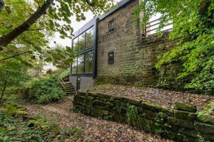 a brick house with a window and a stone wall at The Keep at Castlegate - Luxury detached retreat in Cragg vale, Hebden Bridge in Mytholmroyd