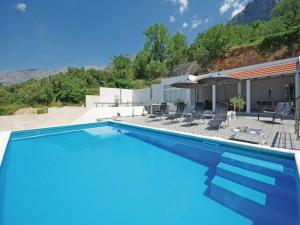 a large swimming pool with chairs and an umbrella at Villa Blanka in Podgora