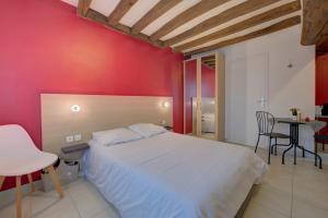 La Petite Maison appartement 1 في Avoine: غرفة نوم بسرير ابيض وجدار احمر