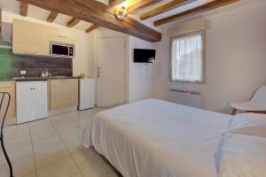een slaapkamer met een wit bed en een keuken bij La Petite Maison appartement 1 in Avoine