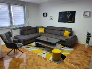 a living room with a gray couch and yellow pillows at Apartment Pallaton in Našice