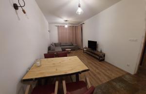 Una sala de estar con una mesa de madera y un sofá. en Buko apartamenty, en Uniejów