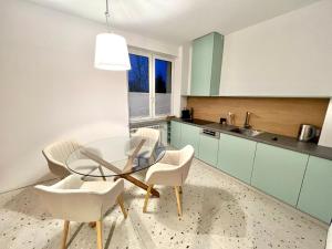een keuken met een glazen tafel en witte stoelen bij Apartament RadMila2 Premium in Radom