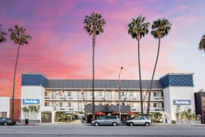 uma representação de um hotel com palmeiras em frente em Travelodge by Wyndham Culver City em Los Angeles