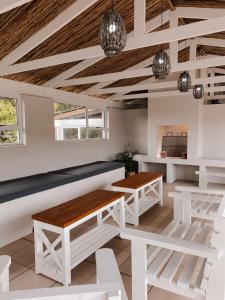 a room with white benches and wooden ceilings at Amblewood Beach Cottages in Kenton on Sea