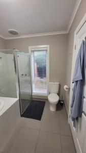 a white bathroom with a toilet and a shower at Quiet family retreat getaway - Wildlife Park, Sovereign Hill, Kryall Castle and city at your door - modern apartment, 8 guests in Ballarat