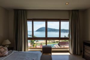 a bedroom with a large window with a view of the ocean at Tina Holiday Homes in Ko Chang