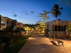 a street with a bench and palm trees at night at Housi, condo beira mar em Milagres in Passo de Camarajibe