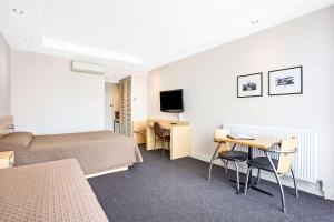 a hotel room with two beds and a desk and a television at Richmond Henty Hotel in Portland