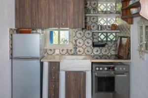 a kitchen with wooden cabinets and a white refrigerator at Alexandros by the Beach - Serifos in Livadakia