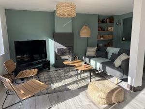 ein Wohnzimmer mit einem Sofa und einem TV in der Unterkunft Maison de campagne entièrement climatisée avec grand jardin in Pressagny l'Orgueilleux