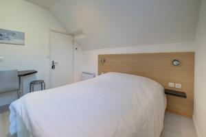 sypialnia z białym łóżkiem i drewnianym zagłówkiem w obiekcie La petite maison 3 w mieście Avoine