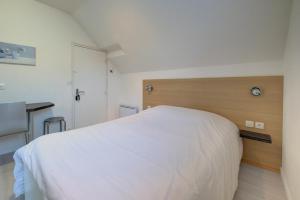 a bedroom with a white bed and a wooden headboard at La petite maison 3 in Avoine