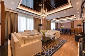 a living room with white furniture and a chandelier at Radisson Blu Leogrand Hotel in Chişinău