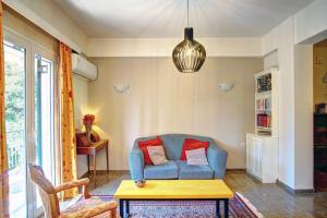 Kellys Apartment في Anemómylos: غرفة معيشة مع أريكة زرقاء مع وسادتين حمراء