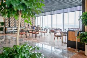 people sitting at tables in a restaurant with large windows at TMS Beachfront Quy Nhon Apartment in Quy Nhon