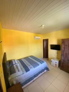 a bedroom with a bed and a yellow wall at Pousada Vitoria Aquiraz in Aquiraz