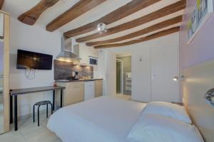 a bedroom with a white bed and a kitchen at La petite maison 4 in Avoine