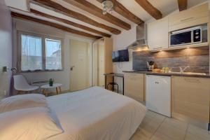 a bedroom with a white bed and a kitchen at La petite maison 4 in Avoine