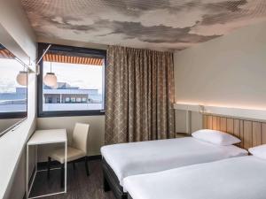 een hotelkamer met 2 bedden en een raam bij ibis Lyon Est Meyzieu in Meyzieu