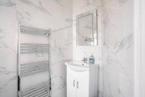 a white bathroom with a sink and a mirror at MOYDOM Cosy Apt sleeps 4 with self breakfast & carpark in Redbridge +9 photos