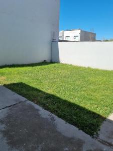 una sombra en la hierba junto a un edificio en rincon lindo en Cipolletti