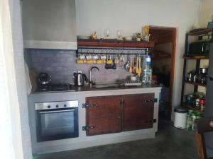 una pequeña cocina con fogones y fregadero en Con piscina a 3 cuadras de la playa, en Balneario Argentino