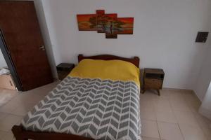 - une chambre dotée d'un lit avec une couverture jaune et grise dans l'établissement Casa con vista a las sierras, à Santa María