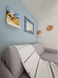 ein Wohnzimmer mit einem Sofa und Gemälden an der Wand in der Unterkunft Maison avec terrasse vue mer à quelques marches de la Fossette in Le Lavandou