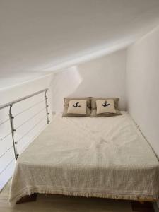 Bett in einem weißen Zimmer mit zwei Kissen darauf in der Unterkunft Maison avec terrasse vue mer à quelques marches de la Fossette in Le Lavandou