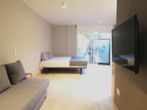 um quarto com uma cama, um sofá e uma televisão em Mazi Apartments Suite em Mataró