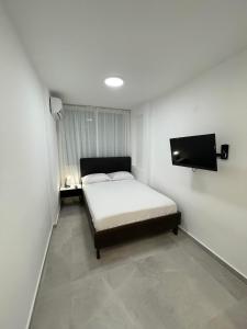 a small bedroom with a bed and a flat screen tv at Apartment Bliss in Bat Yam
