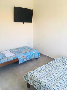 a room with two beds and a flat screen tv at Águas Quentes in Caraguatatuba