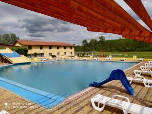 a large swimming pool with chairs and a slide at Ligetalja Termál Apartmanok in Penészlek