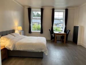 um quarto com uma cama, uma secretária e 2 janelas em Premier 1 Bed Studio B em Broxburn