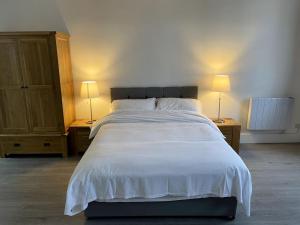 um quarto com uma grande cama branca e 2 candeeiros em Premier 1 Bed Studio B em Broxburn