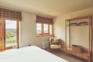 a bedroom with a bed and a chair and windows at Drovers Rest in All Stretton
