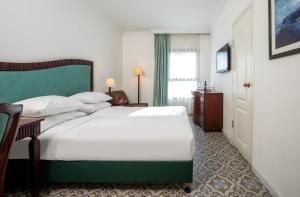 una camera da letto con un grande letto bianco con testiera verde di Jerusalem Gold Hotel a Gerusalemme
