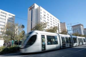 un treno bianco che viaggia lungo una strada di città con edifici di Jerusalem Gold Hotel a Gerusalemme