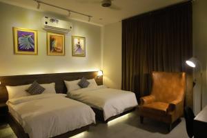 a hotel room with two beds and a chair at Sunset BnB in Karachi
