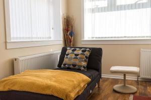 1 dormitorio con 1 cama, 1 silla y 2 ventanas en Cosy & Bright Semi-Detached House en Edimburgo
