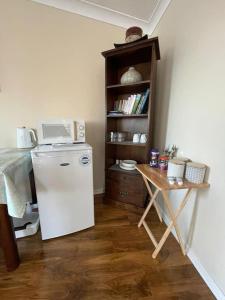 a kitchen with a refrigerator and a table with a microwave at Cosy & Bright Semi-Detached House in Edinburgh