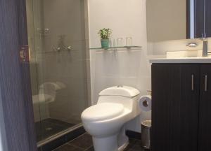 a bathroom with a toilet and a glass shower at Hotel 104 Art Suites in Bogotá