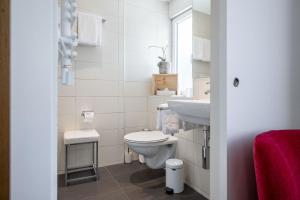 een witte badkamer met een toilet en een wastafel bij Hotel Zur Traube in Brigerbad