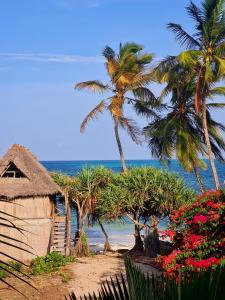 ジャンビアニにあるLadha ya Zanzibar Boutique Guesthouseのヤシの木と小屋と海のビーチ