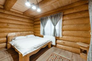 a bedroom with a bed in a log cabin at Rustic Chalet in Călăţele