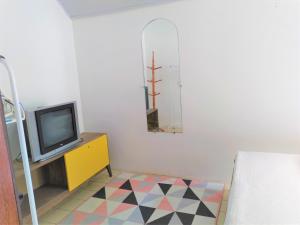 a living room with a tv and a yellow cabinet at Villa Chá by Charibas in Passo de Torres