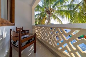 a balcony with two chairs and a palm tree at PrideInn Hotel Diani in Diani Beach